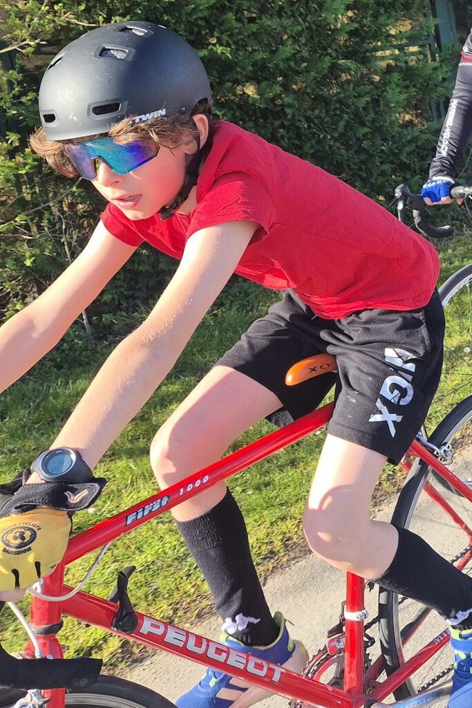 Jeune coureur du Team Vélo Puz en danseuse sur son vélo de route, lors d'un entraînement du club au printemps